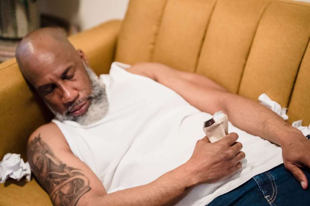 Ultra Bann A man resting on a sofa holding a can, surrounded by crumpled papers, depicting stress and fatigue