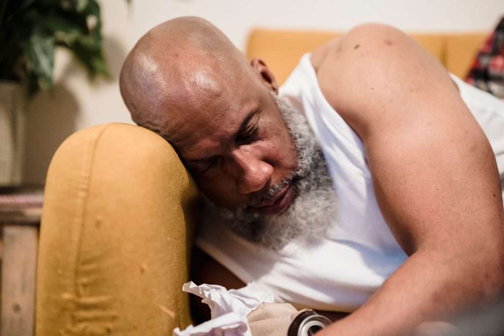 Ultra Bann A bearded man sleeps on a couch, appearing tired in a cozy indoor setting